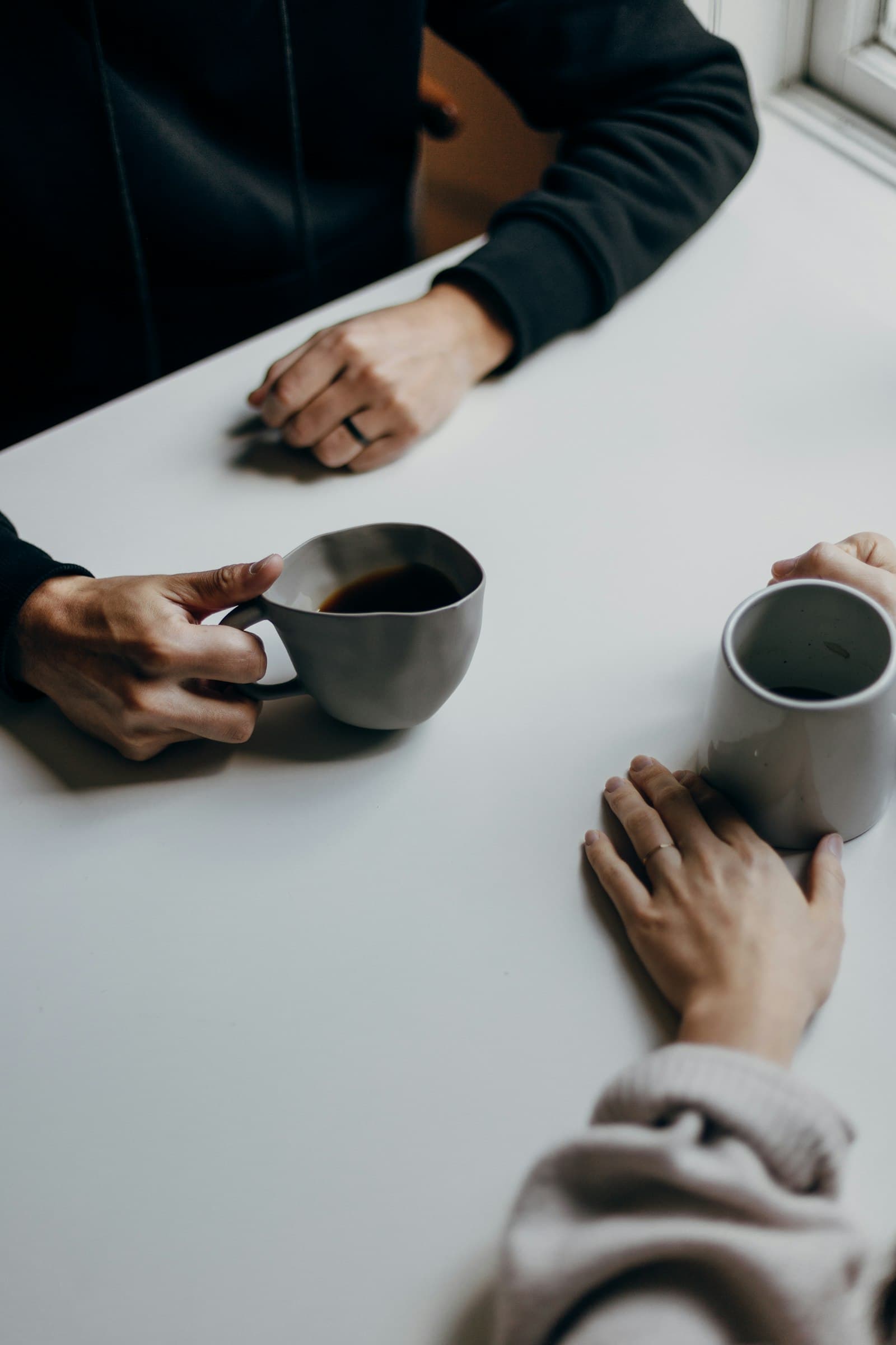 Two people sharing a quiet conversation over warm mugs