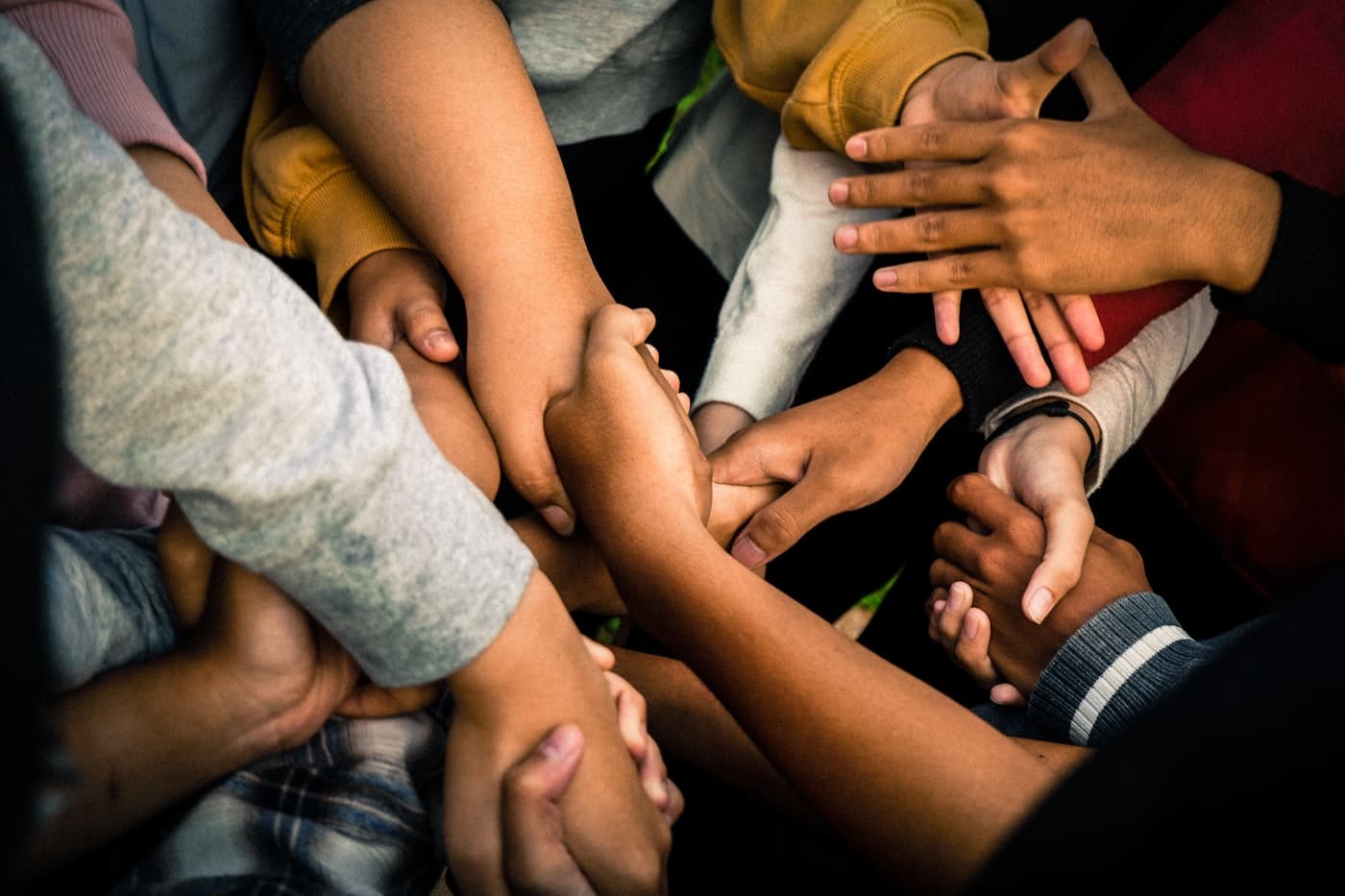 A circle of joined hands from a multicultural group of friends